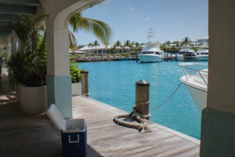 A white high-speed ferry cutting across turquoise open water toward Bimini, wake spray behind it, clear sky, no people, no logos, no readable text.