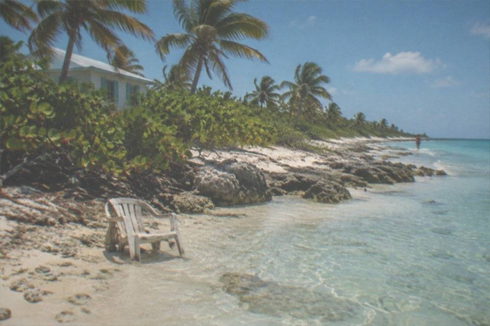 Empty white sand beach with clear shallow turquoise water and palm trees