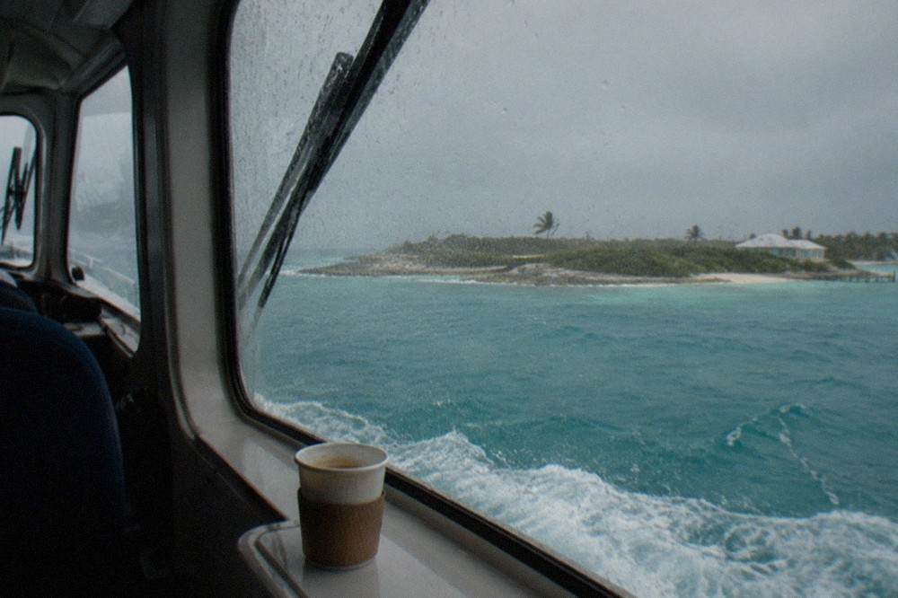 Passenger ferry crossing open turquoise water toward a low Bahamian island