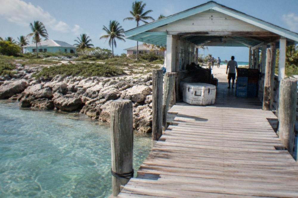 A small ferry terminal building beside a dock with shallow clear water on either side