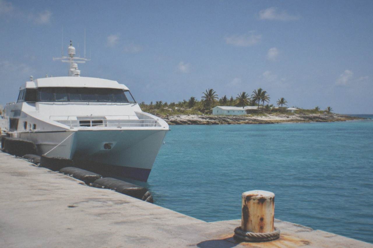 High speed ferry docked at a terminal with blue water and a clear sky