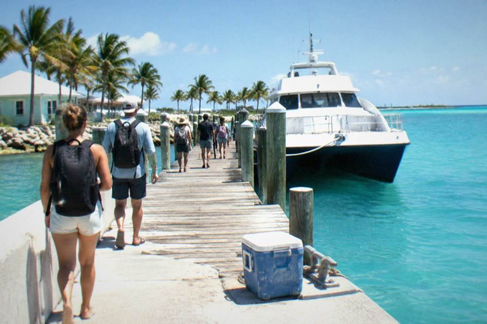 Ferry passengers walking along a dock toward a waiting high-speed vessel