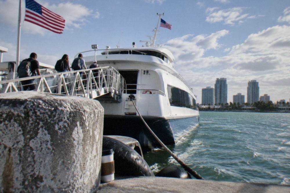 A high-speed ferry at the dock in Fort Lauderdale with passengers boarding up a gangway.
