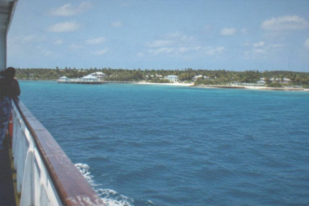 A ferry moving across open blue water toward an island coastline