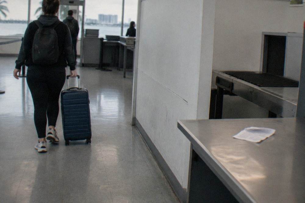 Ferry passengers rolling suitcases through a customs inspection area at a cruise terminal