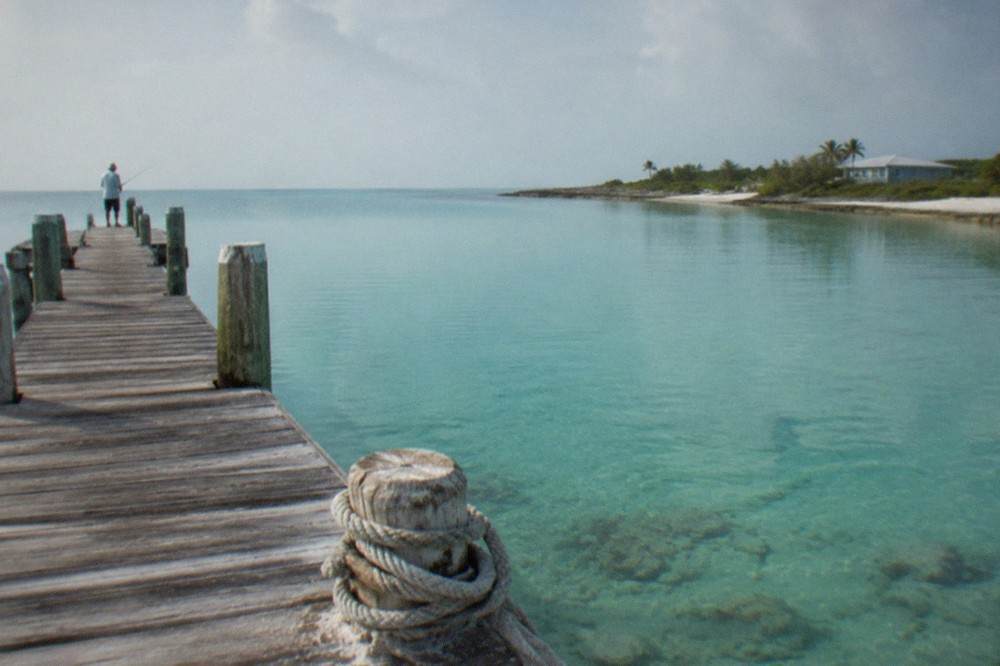 Small wooden dock extending over calm turquoise water on a clear day