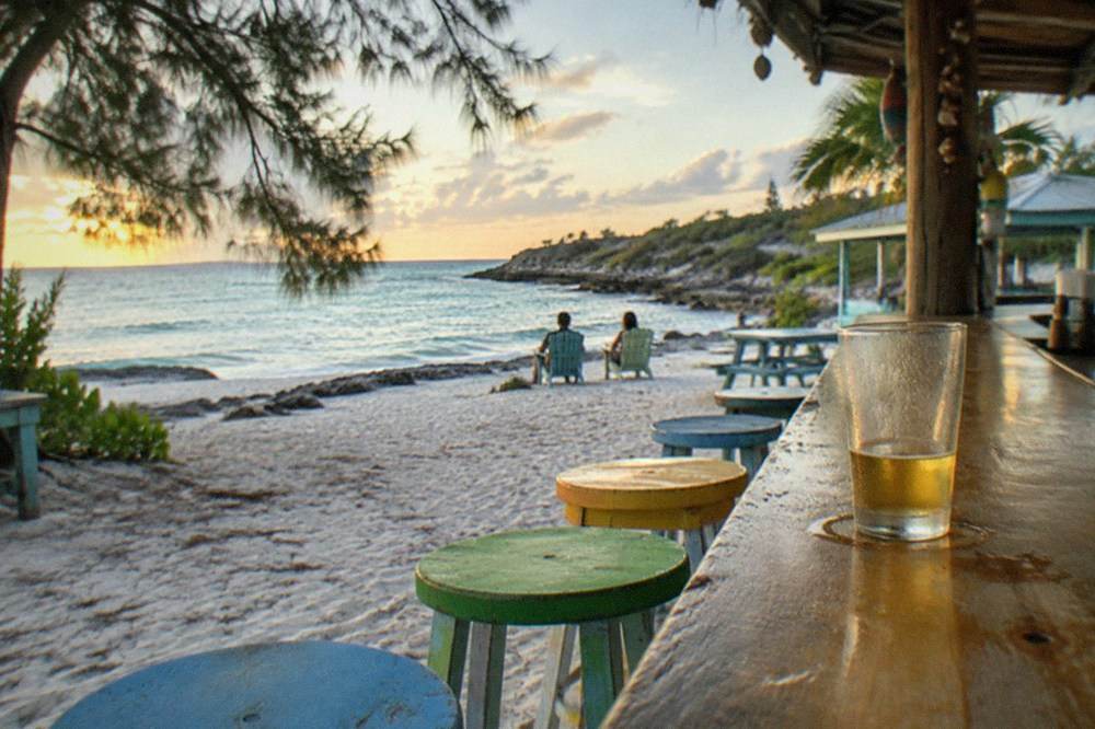 Colorful beachside bar with wooden stools facing the water