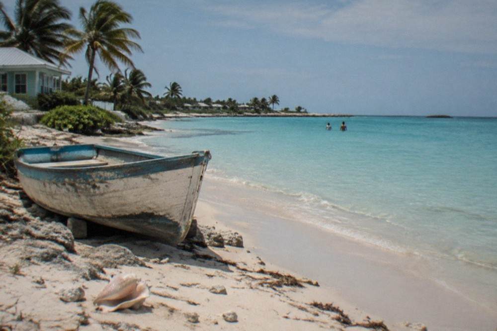A small Bahamian beach with pale sand and calm turquoise water along the shoreline