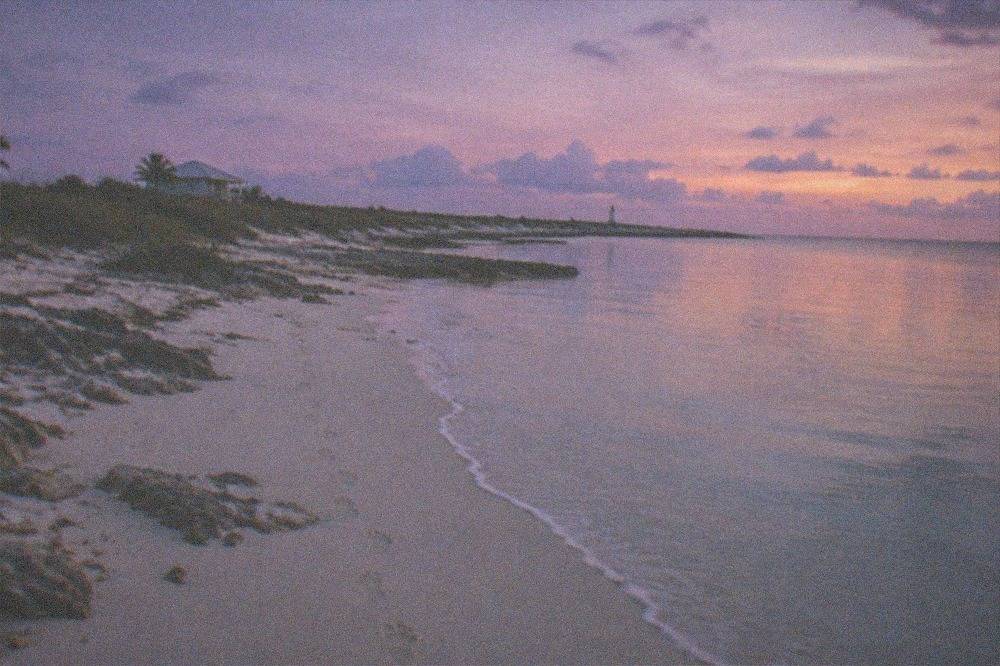 A wide sandy beach on a small Bahamian island with calm shallow water and no swimmers