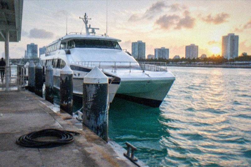 A high-speed ferry leaving a Fort Lauderdale marine terminal bound for Bimini, calm turquoise water, no people, no logos, no readable text.