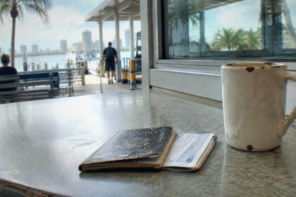 Passport and boarding pass resting on a counter beside a ferry terminal window