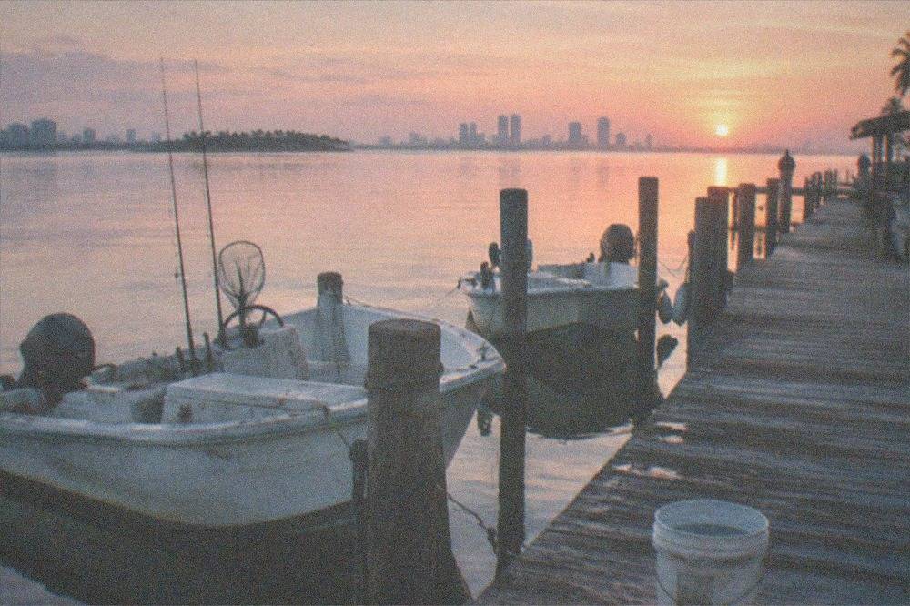 Sunrise over a calm marina with small boats moored along a wooden dock