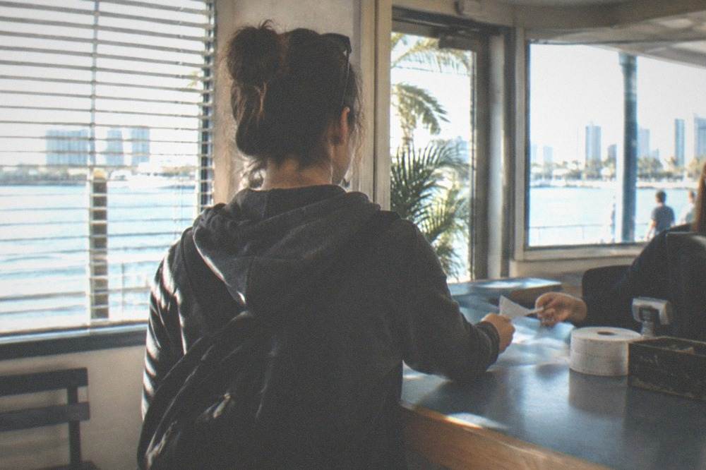 Traveler handing a document across a ticket counter at a ferry check-in desk