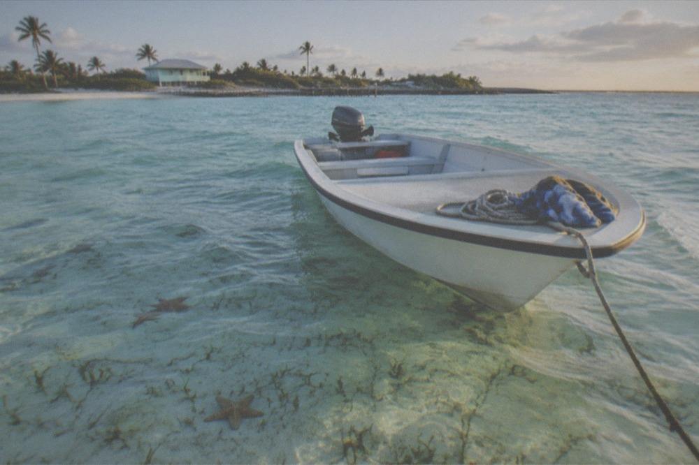 Small boat anchored in clear shallow water near a beach