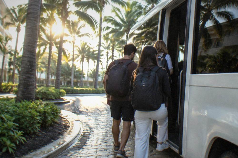 Travelers boarding a shuttle bus outside a hotel in the morning