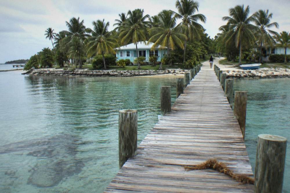 Wooden dock extending over clear shallow water toward a small island