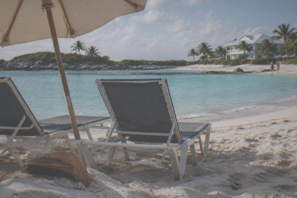 Beach chairs and umbrella on white sand beside calm turquoise water