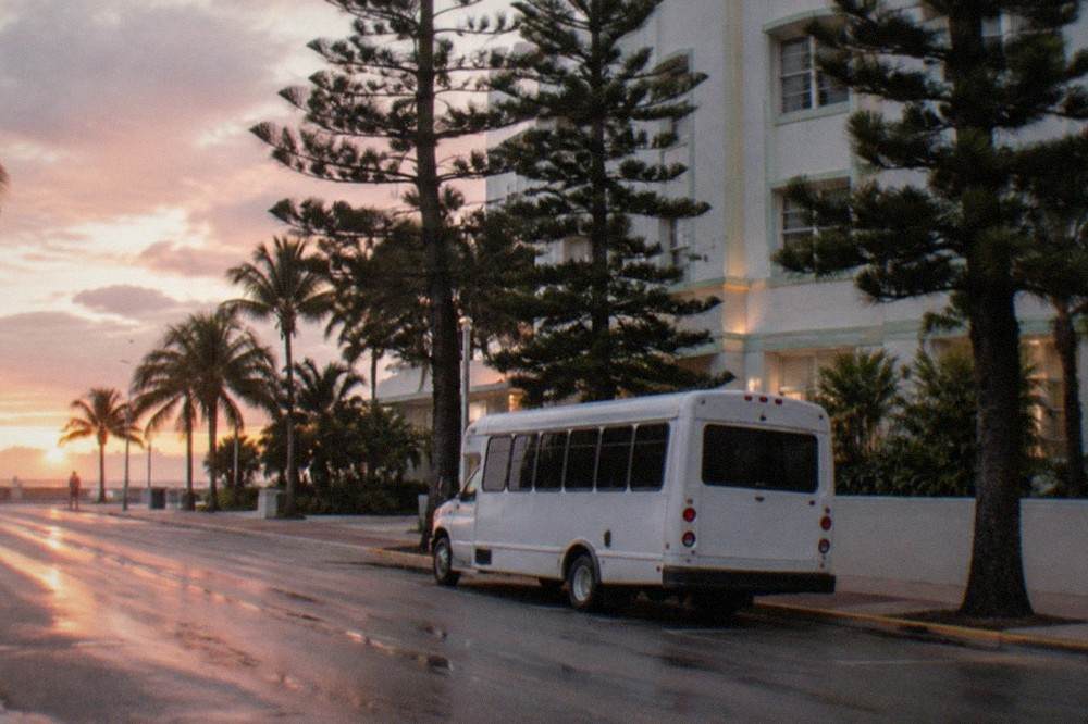 A shuttle bus waiting outside a Miami Beach hotel entrance at sunrise