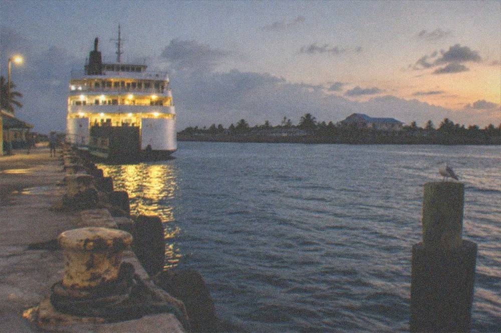 A ferry terminal at dusk with the vessel's lights reflecting on the water