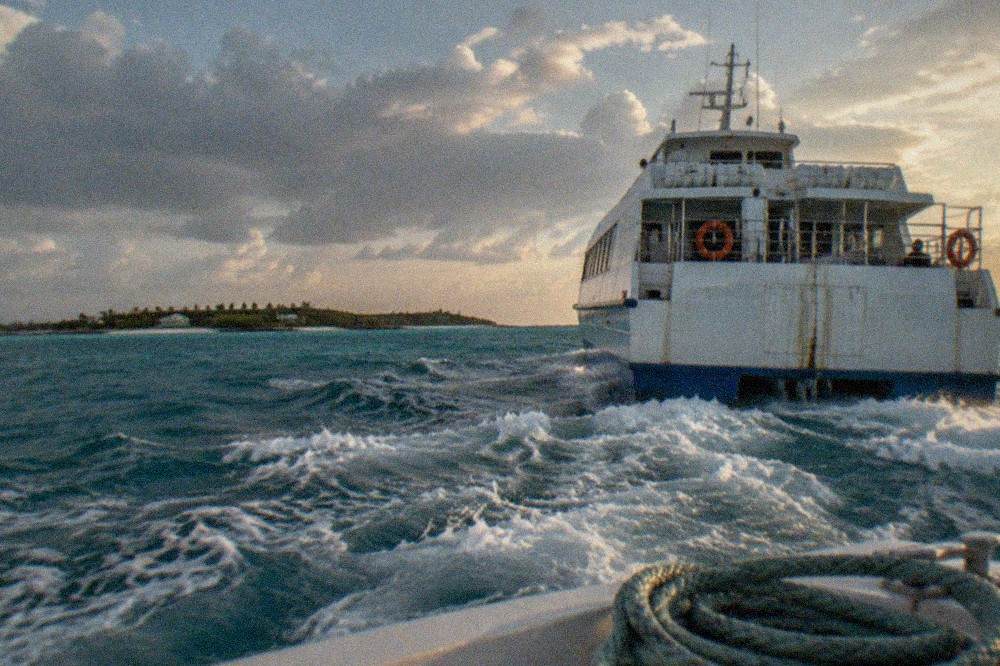 High speed ferry underway on open water with a distant island on the horizon