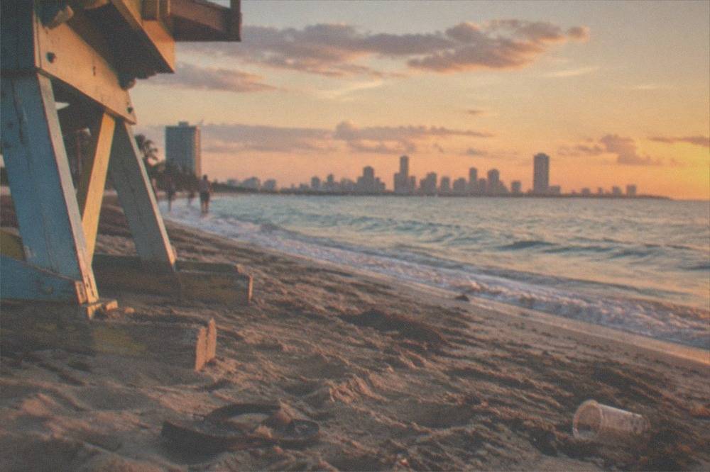 Wide sandy beach with calm water and distant skyline at golden hour