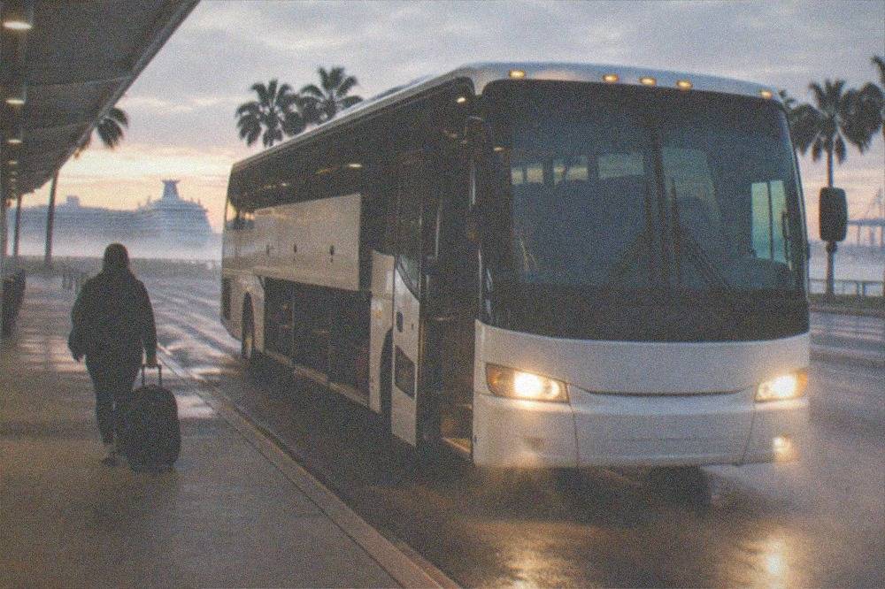 Tour bus parked outside a ferry terminal with passengers boarding