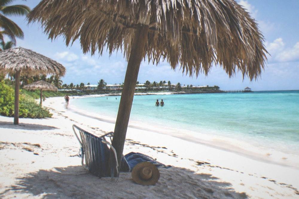 Quiet Caribbean beach with turquoise water and a few thatched shade umbrellas