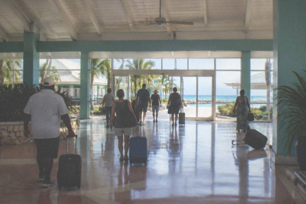Travelers with small bags walking through a ferry terminal toward the gangway