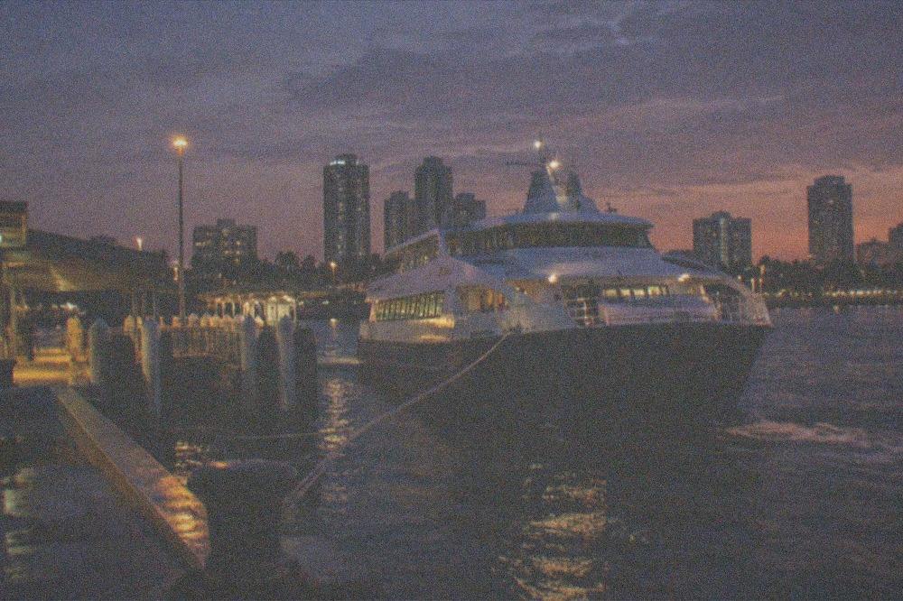 Ferry arriving back at the port at dusk with city lights in the distance