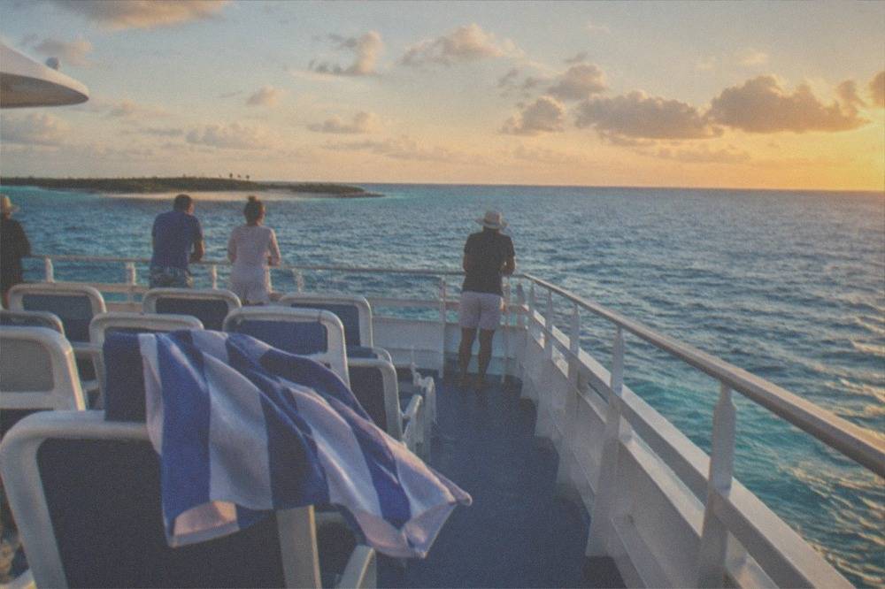 Ferry passengers looking out at open ocean from an upper deck