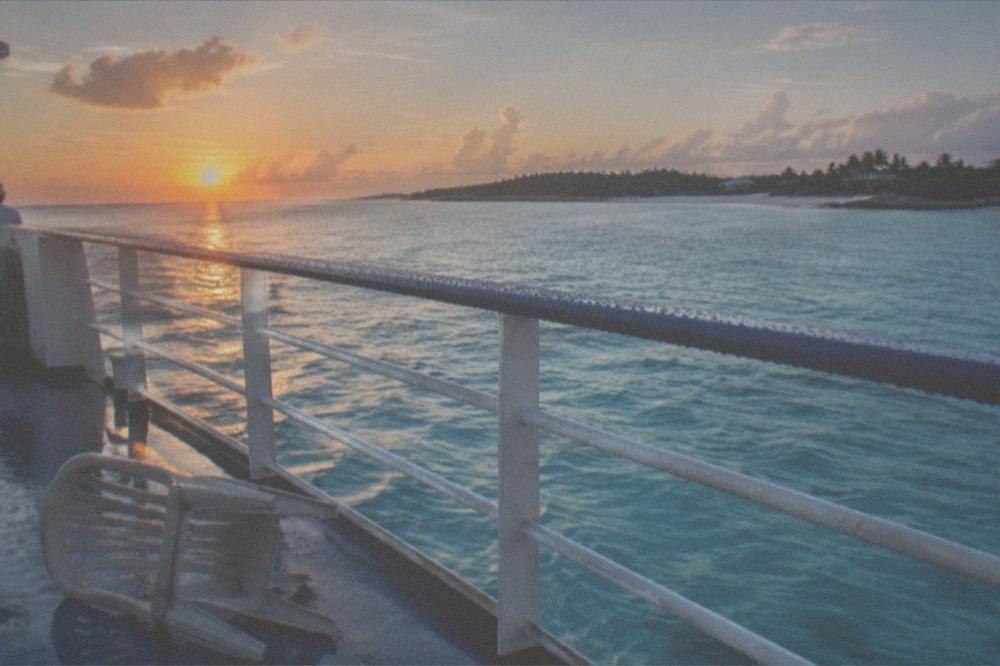 Calm turquoise sea at sunrise seen from a ferry deck railing