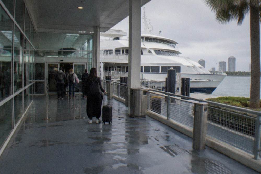 Passenger ferry terminal building with a moored vessel and passengers waiting at the gate
