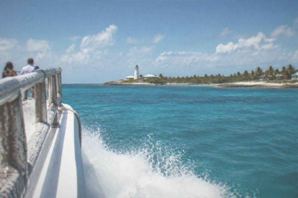 Ferry vessel underway on open water with spray at the bow and clear sky