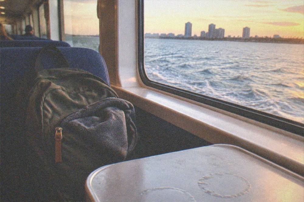 A single soft day backpack resting on a ferry deck seat beside a jacket